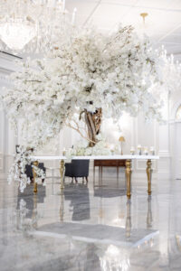 Class Event Rentals Wedding in white theme with Athena table adorned with white flowering tree, shown at an angle