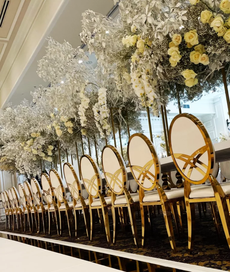 Class Event Rentals luxurious wedding set up showing a line of Giovanna white dining chairs with gold frames ready for guests