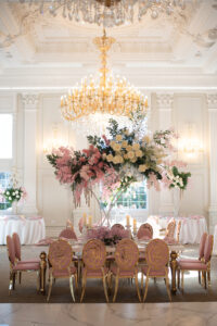 Class Event Rentals Rosabelle Chairs in pink and gold with Athena table in wedding dining setup with flowers and chandeliers