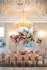 Class Event Rentals Rosabelle Chairs in pink and gold with Athena table in wedding dining setup with flowers and chandeliers