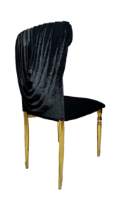 A luxurious black velvet chair with gold-tipped legs, elegantly draped with a plush velvet throw, isolated on a transparent background.