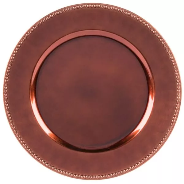 A top view of a circular copper charger plate with an embossed dot pattern along the rim.